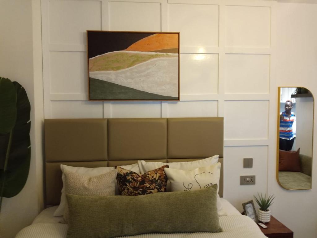 a bedroom with a bed with pillows and a painting on the wall at Nairobi West Studio apartment close to town in Nairobi