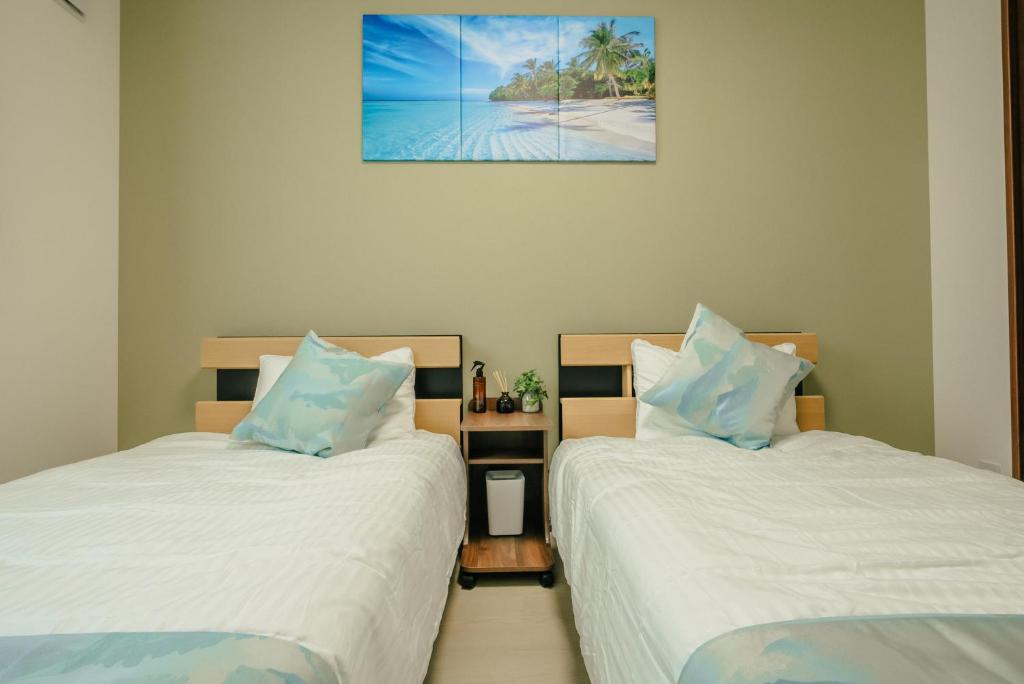 zwei Betten nebeneinander in einem Zimmer in der Unterkunft Value Residence 与那覇 プール 無料レンタカー付 in Miyako-jima