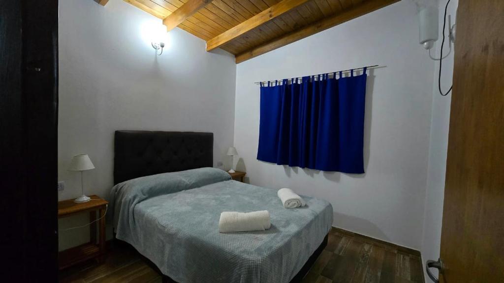 Un dormitorio con una cama y una cortina azul. en Hogar Lejano Cabañas y Río - Huerta Grande - Sierras de Córdoba, en Huerta Grande