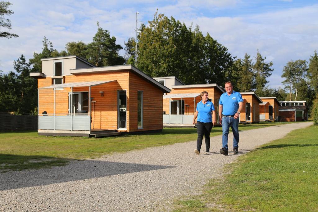 um homem e uma mulher a andar em frente a uma casa em Læsø Camping & Hytteby em Vesterø Havn