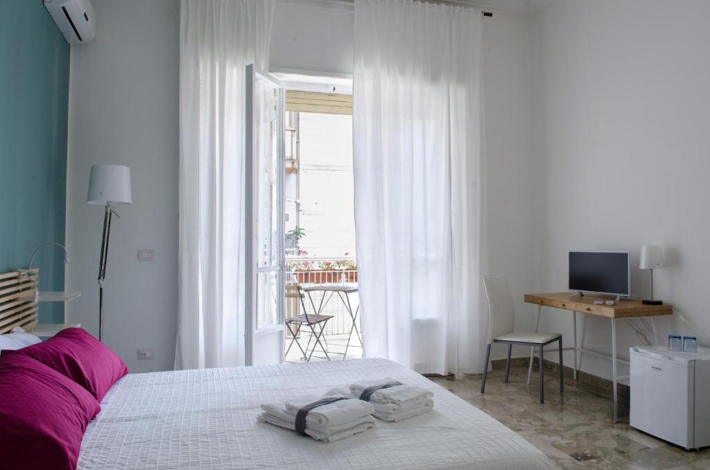 Un dormitorio blanco con una cama con toallas. en B&B Casa Rosellina, en Palermo