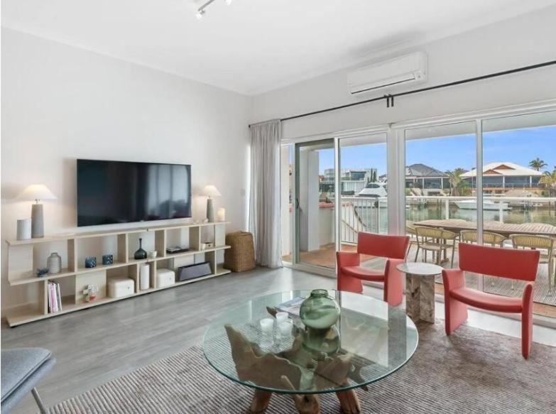 a living room with a television and a table and chairs at Port Sails Escape in Mandurah