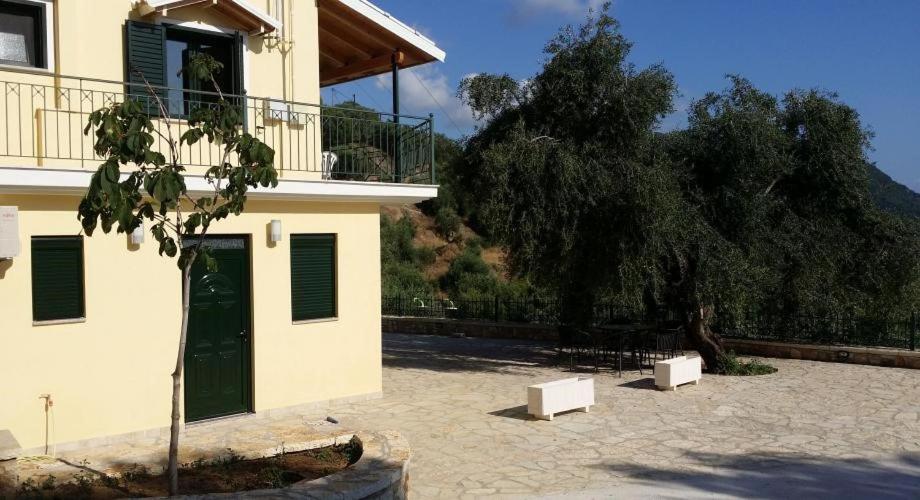 a building with a green door and a tree at Sivota Apartments in Syvota