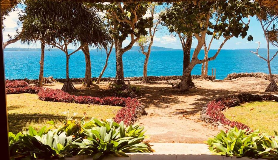 ein Garten mit Bäumen und Blumen vor dem Meer in der Unterkunft Seahorse Lodge - Port Vila's WOW Factor! Huge 5 Bedroom, 3 Bath Seaside Paradise in Port Vila