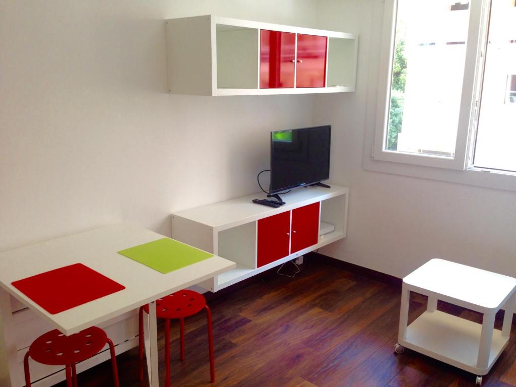 Cette petite chambre dispose d'une table et d'un bureau avec une télévision. dans l'établissement Studio La Reine Astrid, à Antibes