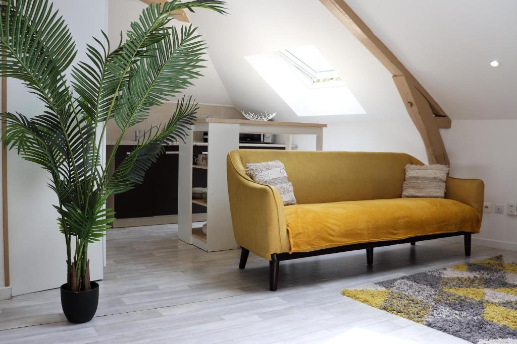 a yellow couch in a living room with a plant at Appartement 2 chambres in Charleville-Mézières