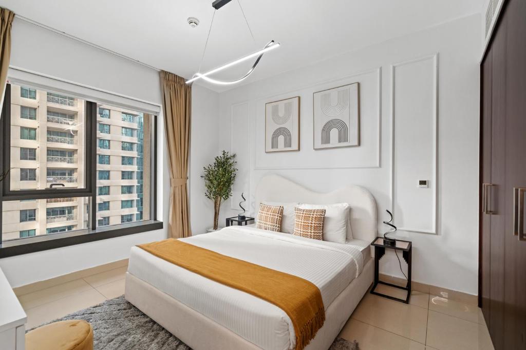 a white bedroom with a bed and a large window at White House With Burj Views, Free Parking in Dubai