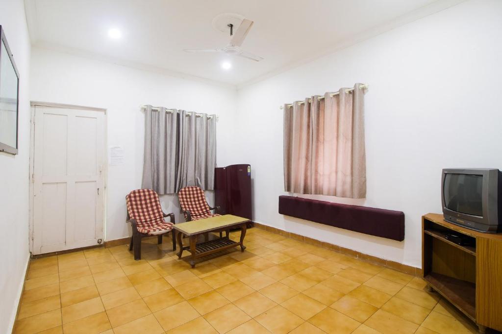 a room with two chairs and a table and a tv at Hotel O Halcyon Inn in Candolim