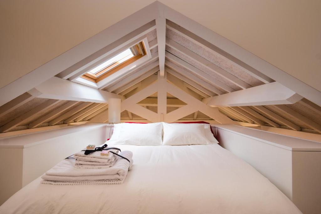a small attic room with a bed and a skylight at Porto By Heart in Porto