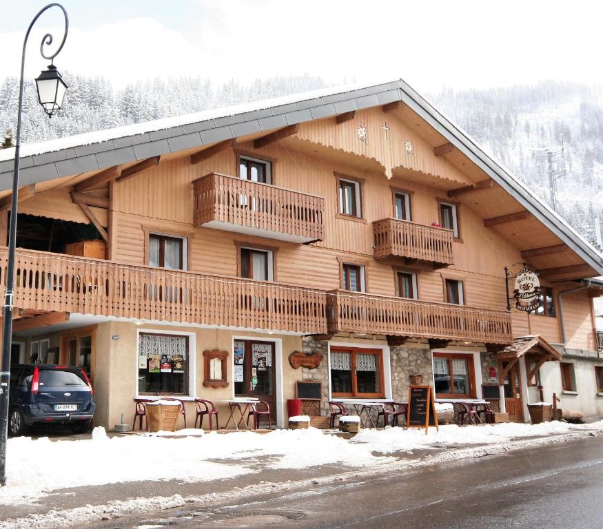 un grand bâtiment en bois avec de la neige au sol dans l'établissement Hôtel l'Edelweiss, à Châtel