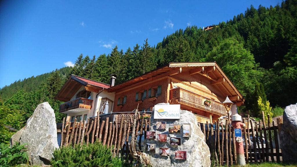 une maison en bois avec un panneau devant elle dans l'établissement Romantikferienhaus am Brändle, à Nesselwängle