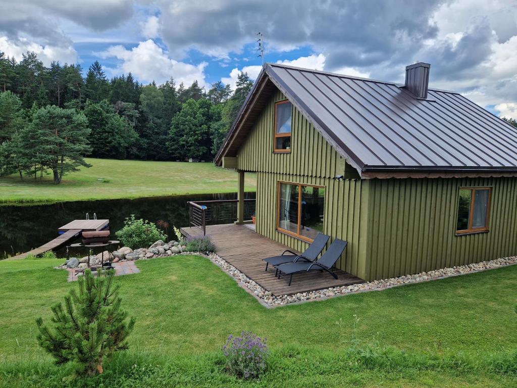 a green house with a deck and a picnic table at VIP forest dreams villa 2 in Leliūnai