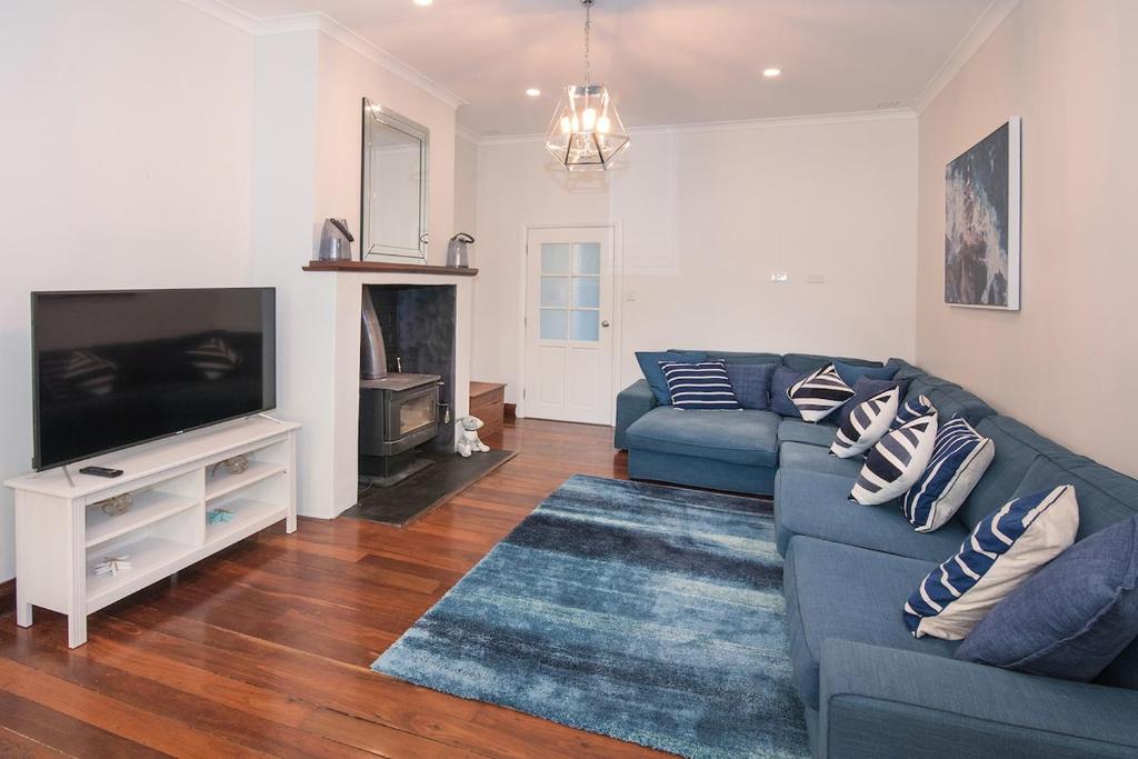 een woonkamer met een blauwe bank en een televisie bij All Decked Out- WIFI, AC in bedrooms, Fireplace in Busselton