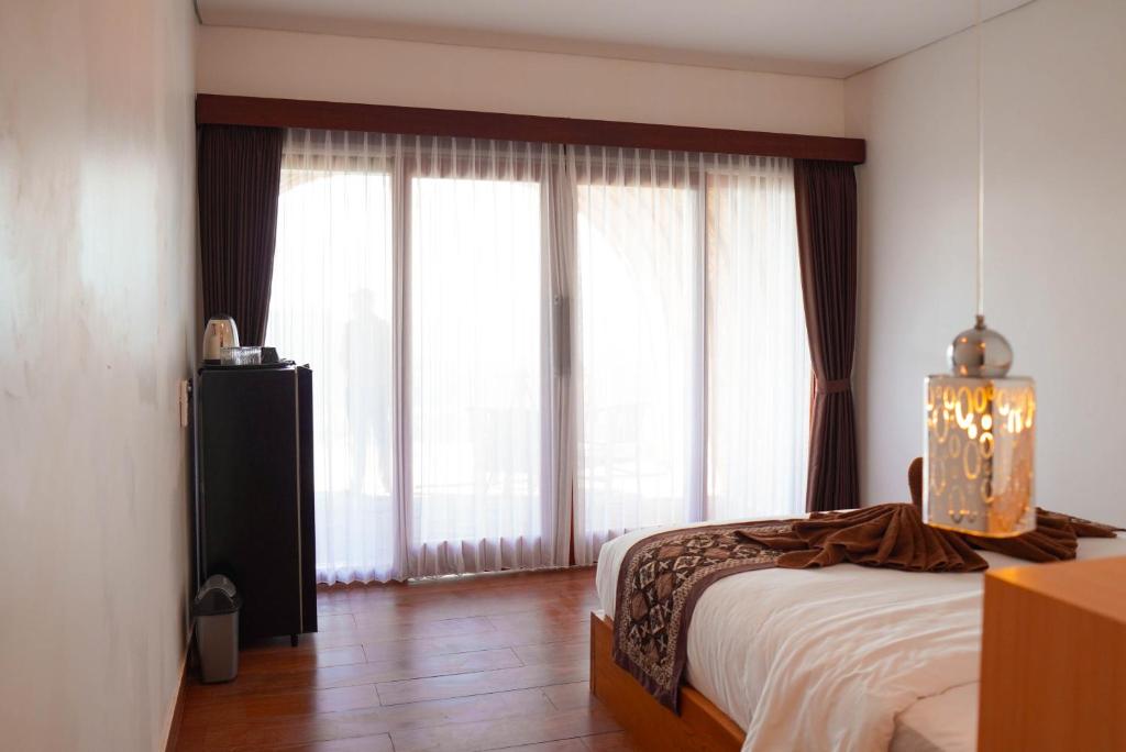 a bedroom with a bed and large windows at Pinggan Skyline in Baturaja