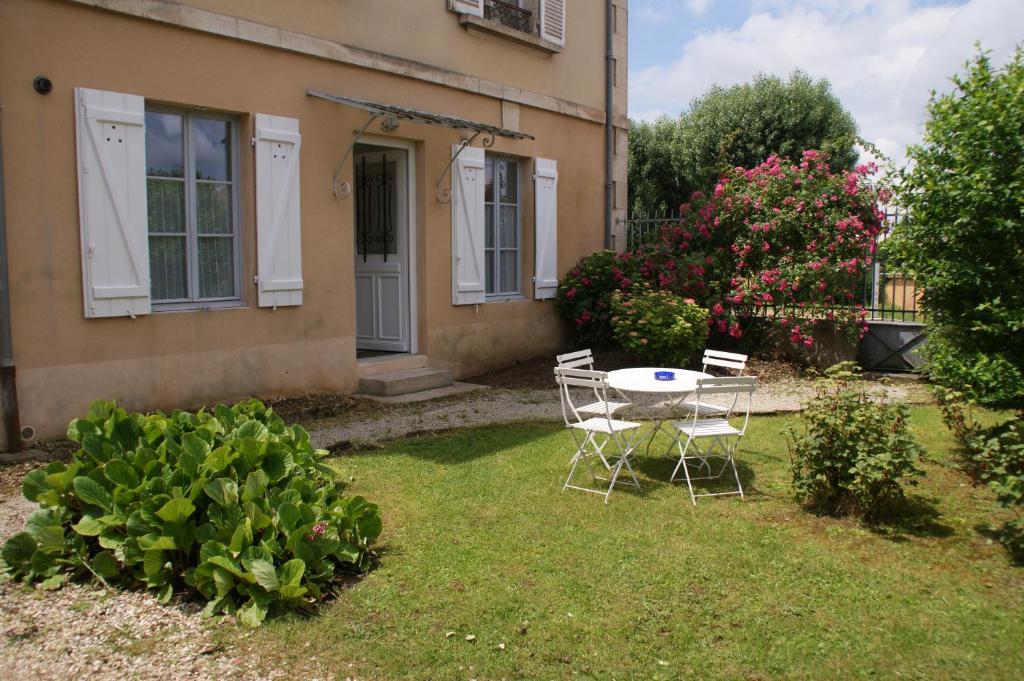 - une table et des chaises dans la cour d'une maison dans l'établissement Gîte Les Minimes, à Avallon