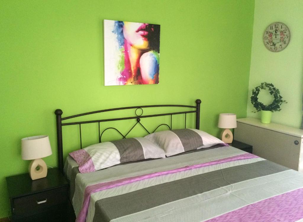 een slaapkamer met een bed en een groene muur bij Kalispera Apartment in Nafplio
