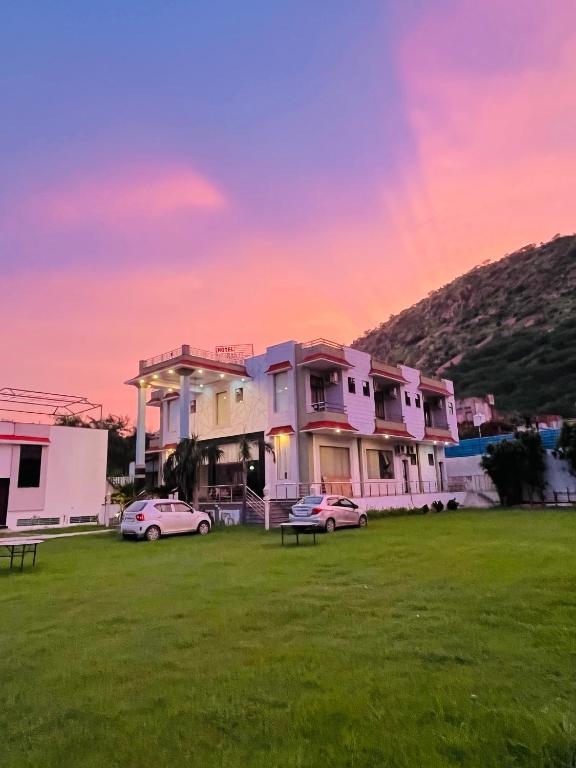 a building with two cars parked in a field at Hotel & Resort Virasat inn in Alwar