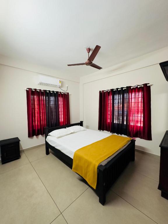 a bedroom with a bed and two red curtains at Malabar Service Apartments in Cochin