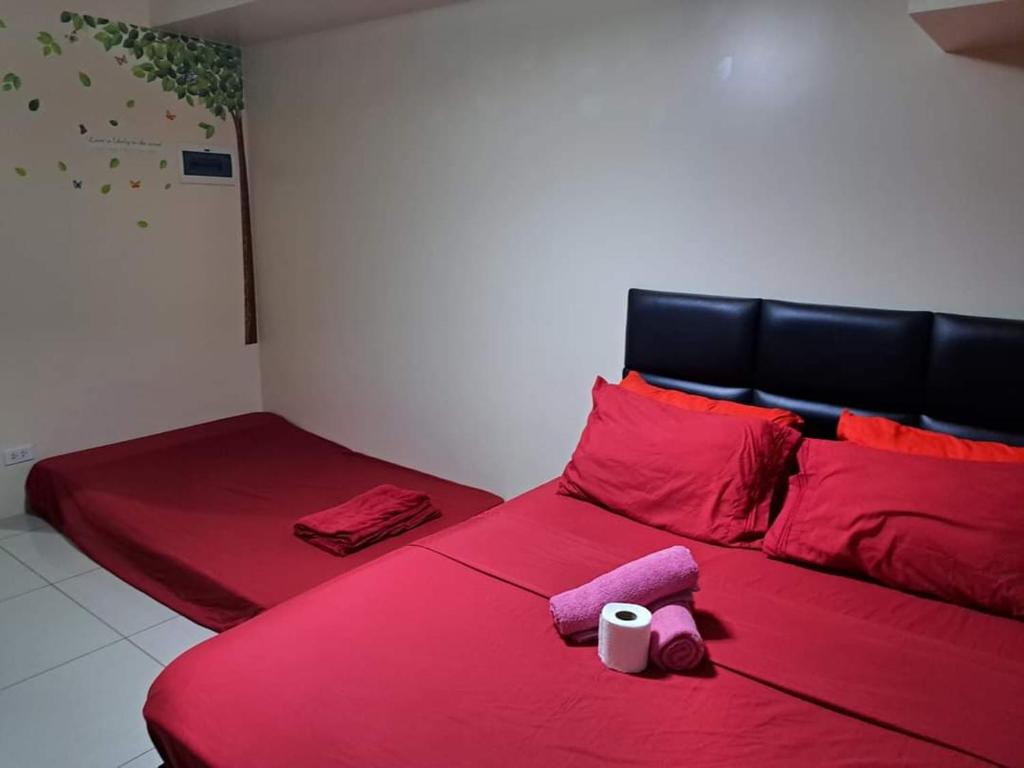 a red bed with red pillows and a roll of toilet paper on it at Studio Condo Horizon Condominium in Cebu City