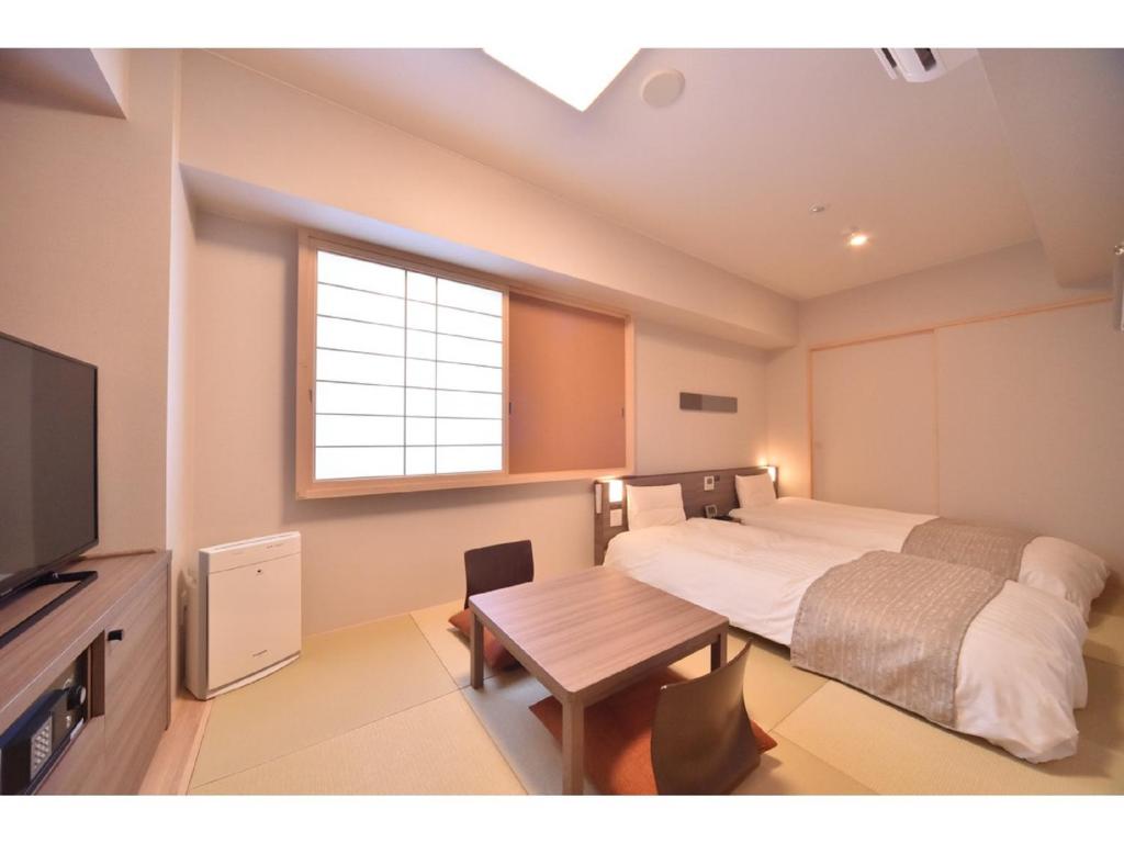 a bedroom with a bed and a table and a television at Dormy Inn Abashiri in Abashiri