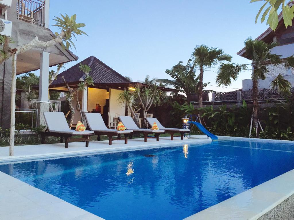 a swimming pool with chaise lounge chairs next to a resort at Kubudiuma Villas Bali in Canggu