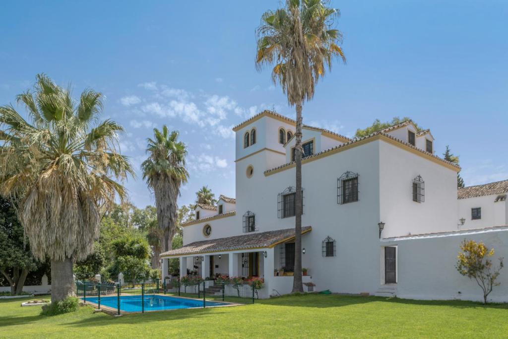 una vista esterna di una casa con palme di Cortijo La Dehesa del Pilar a Setenil