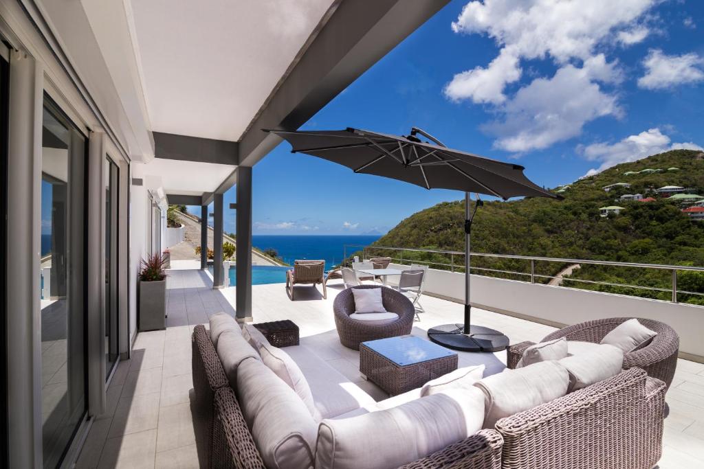 a patio with a couch and chairs and an umbrella at Villa Angel Sunset in Gustavia