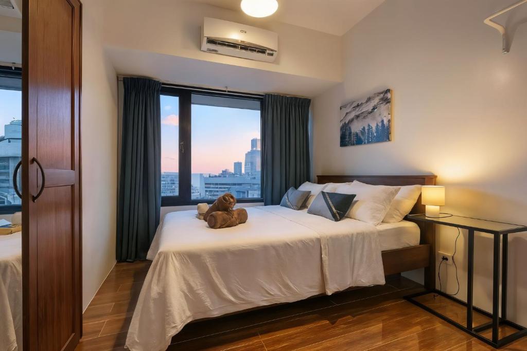 a teddy bear sitting on a bed in a bedroom at Makati 1BR with Skyline View at Air Residences in Manila