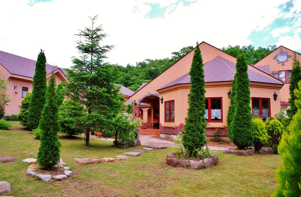 a house with cypress trees in the front yard at Aromatic Garden Villa La Poltrona in Nasu