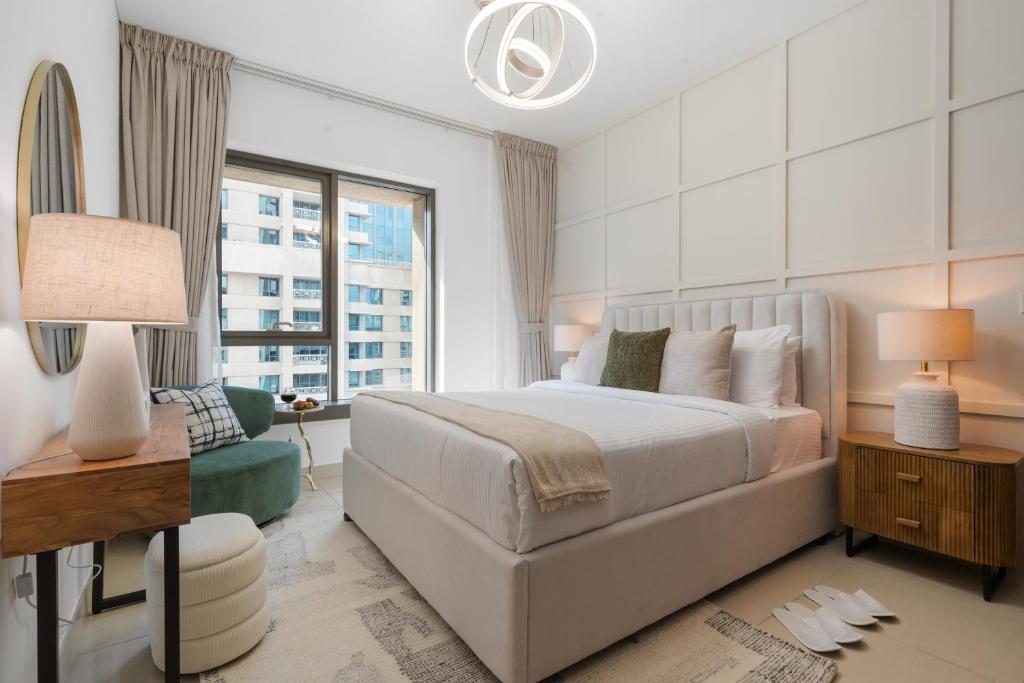 a white bedroom with a bed and a window at Burj Khalifa Fireworks View Downtown - One Bedroom Apartment in Dubai