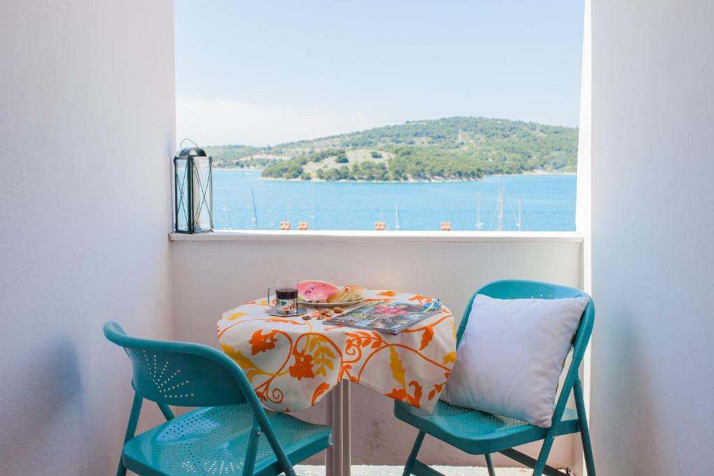 a table and chairs with a view of the water at Hana Home - Apartments Tisno in Tisno