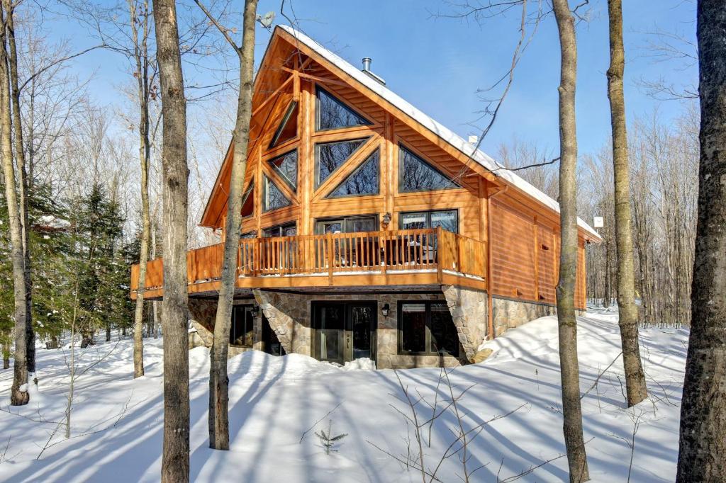 a log cabin in the woods in the snow at Authentic Log Cabin - Billard Spa - Le Scandinave in Saint-Rémi-dʼAmherst