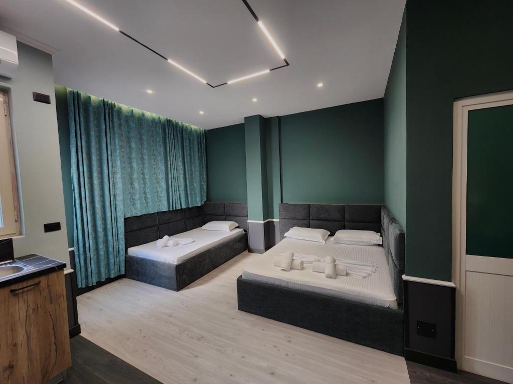 Dos camas en una habitación con paredes verdes. en Aura Hotel, en Durrës