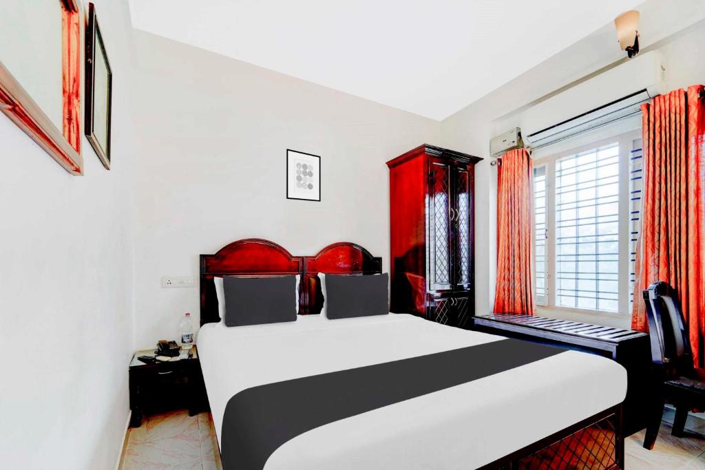 a bedroom with a black and white bed and a window at Hotel O Chalai Bazaar Near Railway Station in Trivandrum