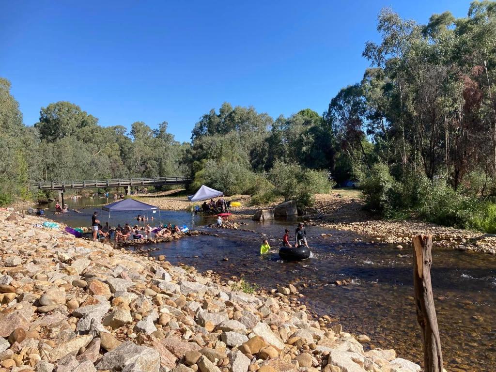 King River Caravan Park في Whitfield: مجموعة من الناس يجلسون في الماء بالقرب من النهر