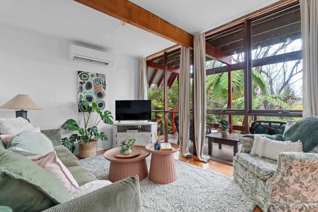 a living room with a couch and a tv at 'The Aerie' Bushland A-frame Escape with Retro Charm in Katoomba