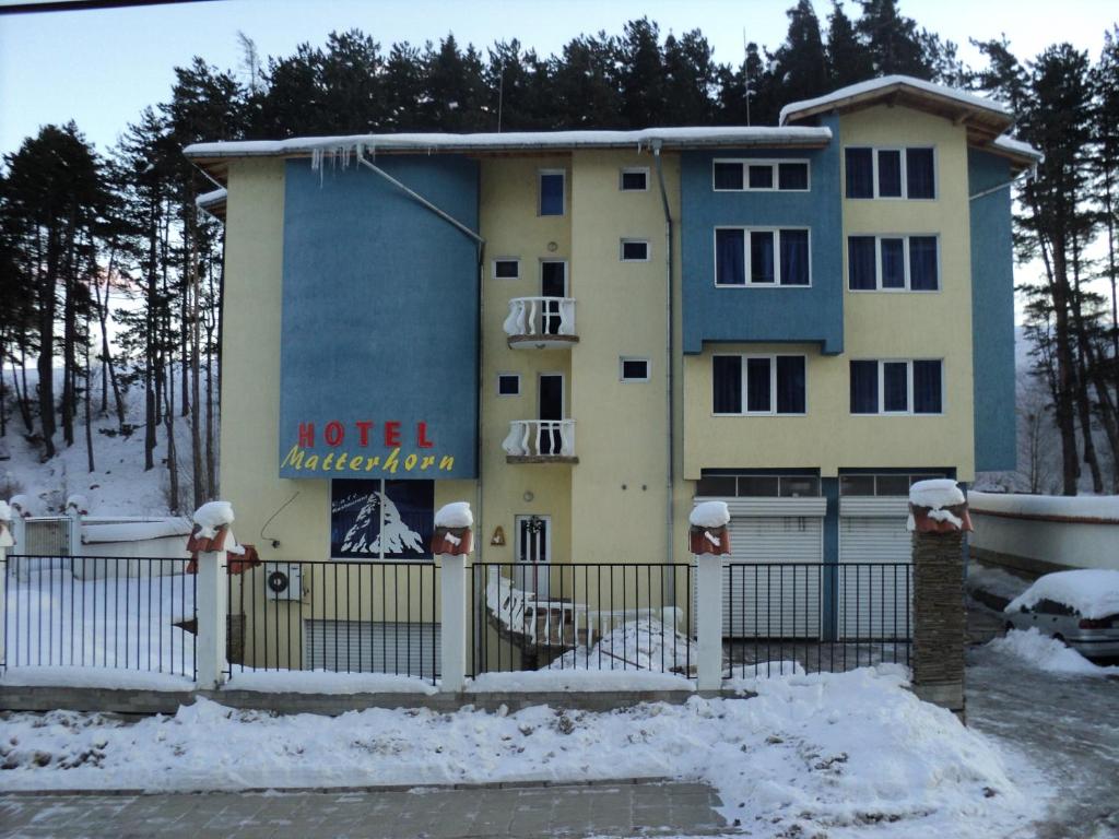 a building with a fence in the snow at Hotel Materhorn in Razlog