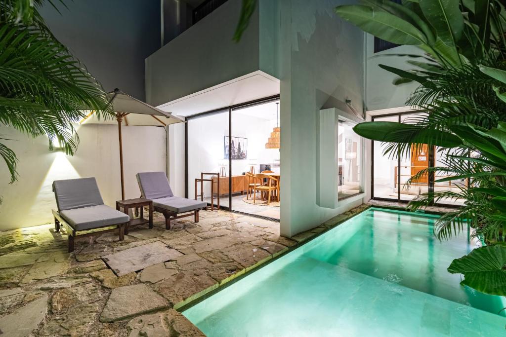 une maison dotée d'une piscine avec deux chaises et une table dans l'établissement Villa Castello di Quassolo, à Canggu