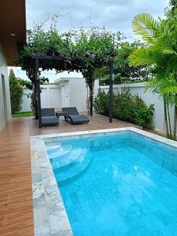 a pool with two chairs and a pergola at Anchan Gardens Pool Villa 23 in Hua Hin