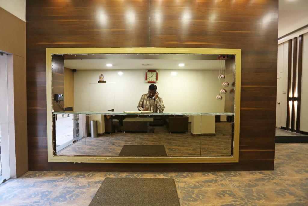 un hombre parado frente a un espejo en una habitación en Hotel O Rajdoot Gaurav, en Bhopal