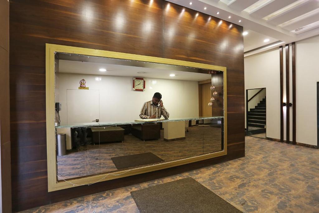 ボーパールにあるHotel O Rajdoot Gauravのロビーの大きな鏡の中に立っている男性