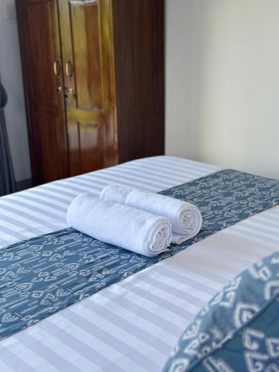 two rolls of towels are sitting on a bed at Merta House Sidemen in Sidemen