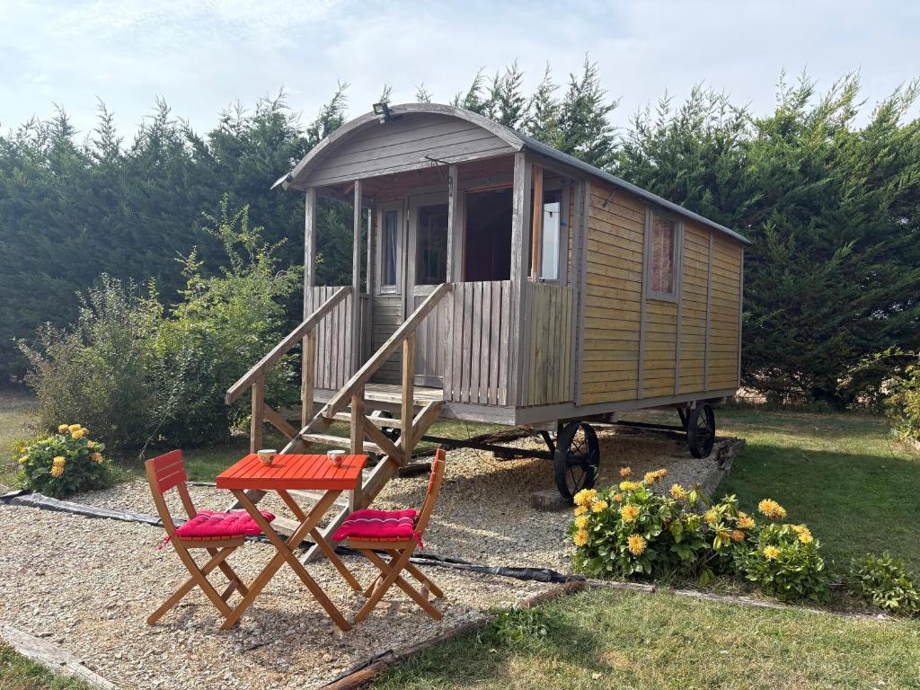 een klein huisje op wielen met twee stoelen bij Terres du Calvados 