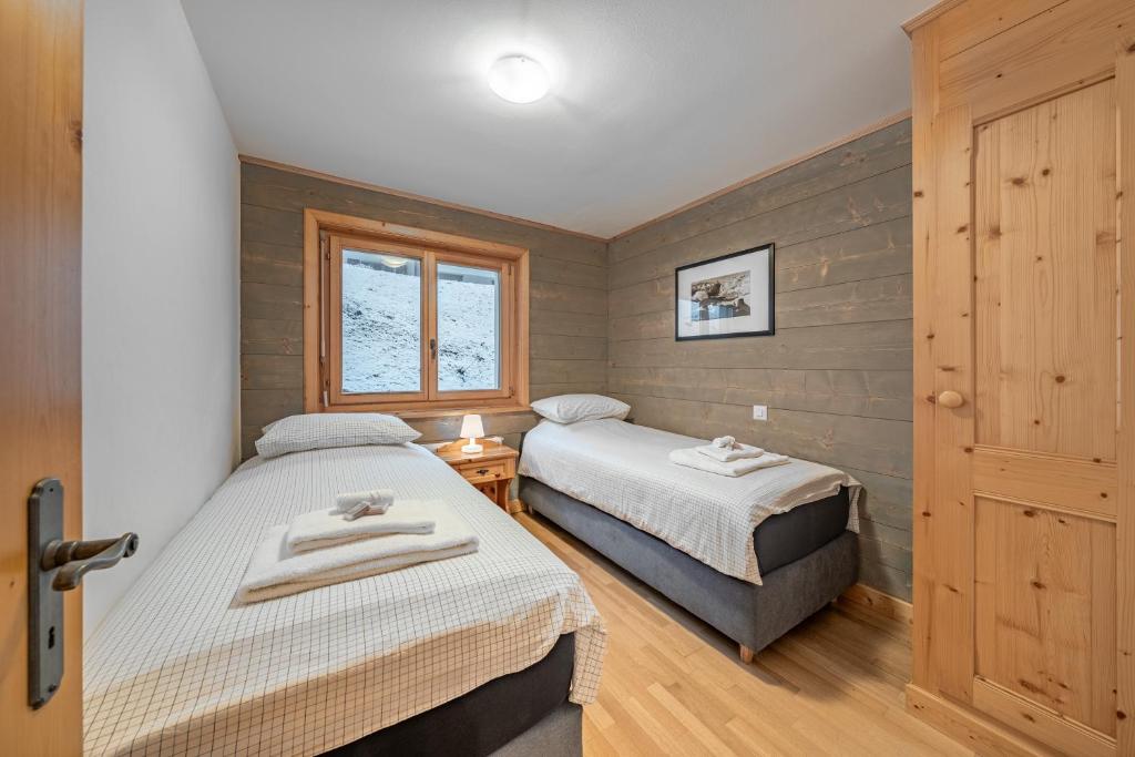 two beds in a small room with a window at Ride Inn Verbier - B&B - private small twin room, shared bathrooms in Verbier