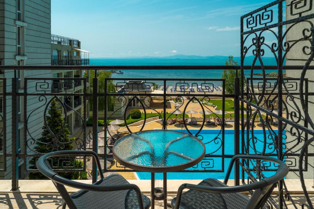 a balcony with a table and chairs and a pool at Festa Pomorie Resort in Pomorie