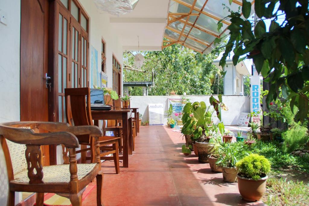 a patio with tables and chairs and potted plants at Pearl Resort Mirissa in Mirissa