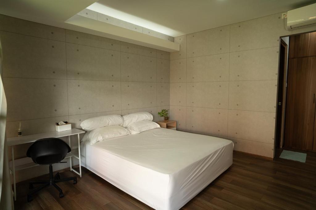 Un dormitorio con una cama blanca y un escritorio. en SS21 Hidden Gem in Jakarta, en Yakarta