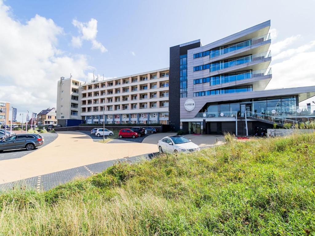 a large building with cars parked in a parking lot at Apartment near North Sea and Lighthouse in Egmond aan Zee