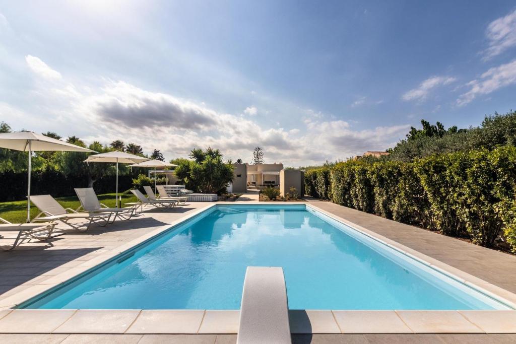 a swimming pool with chairs and umbrellas on a building at Villa Luisa in Noto Marina
