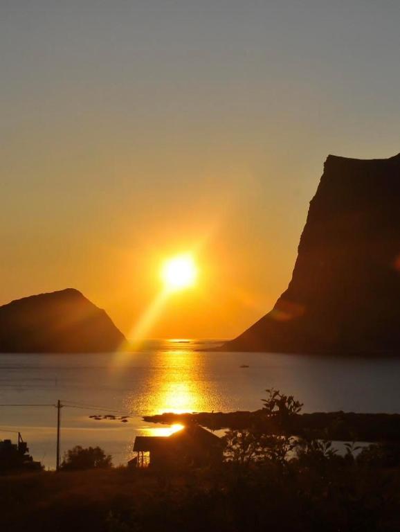 a sunset over a body of water with a mountain at Cabin Panorama Lofoten with Jacuzzi Magic view in Offersøya